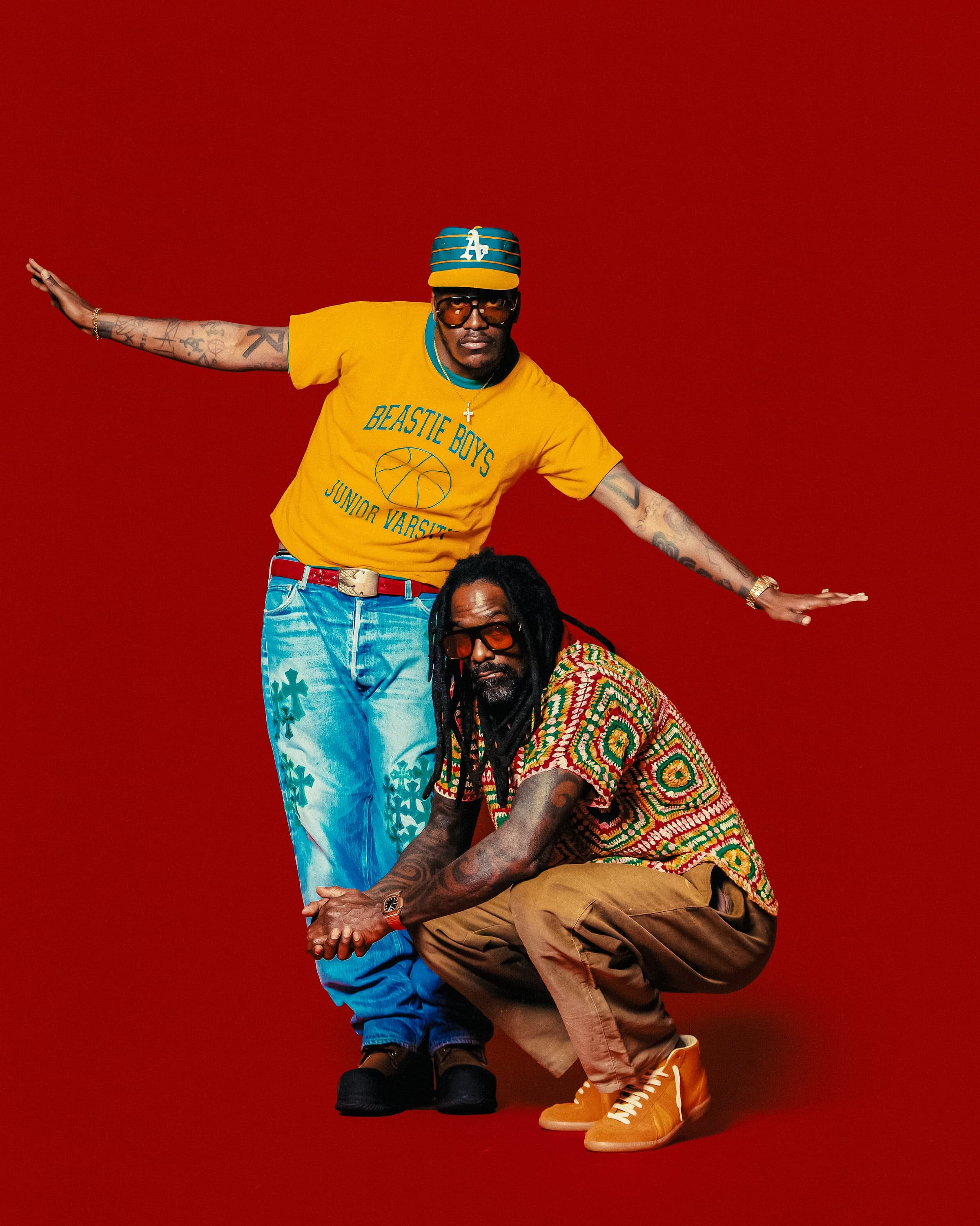 Lil Yachty standing with arms outstretched in a yellow "Beastie Boys" tee and cross-embroidered denim, Shannon McCollum crouched in front in a crochet shirt, red seamless