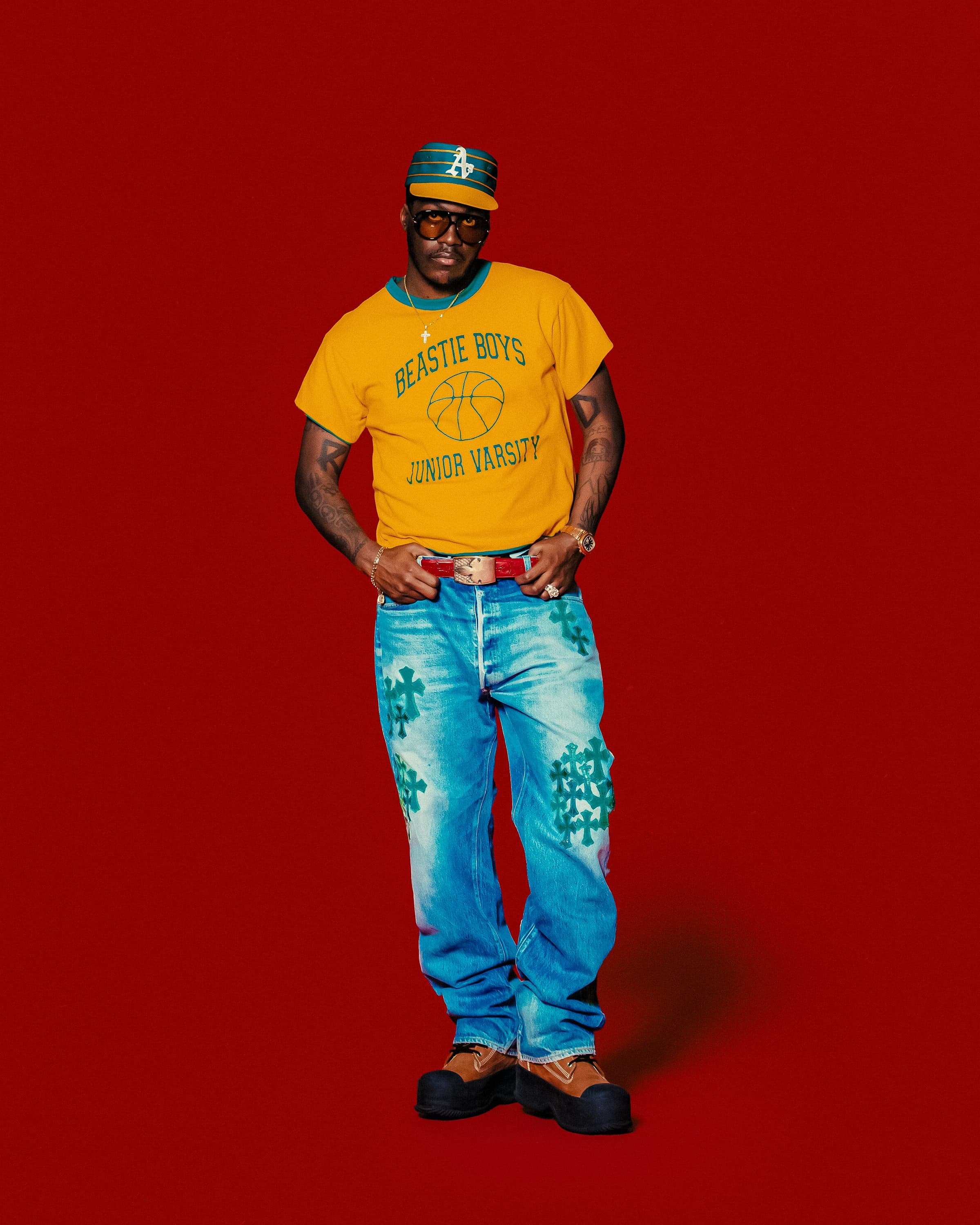Lil Yachty standing solo in a yellow "Beastie Boys" tee and teal cap, red seamless