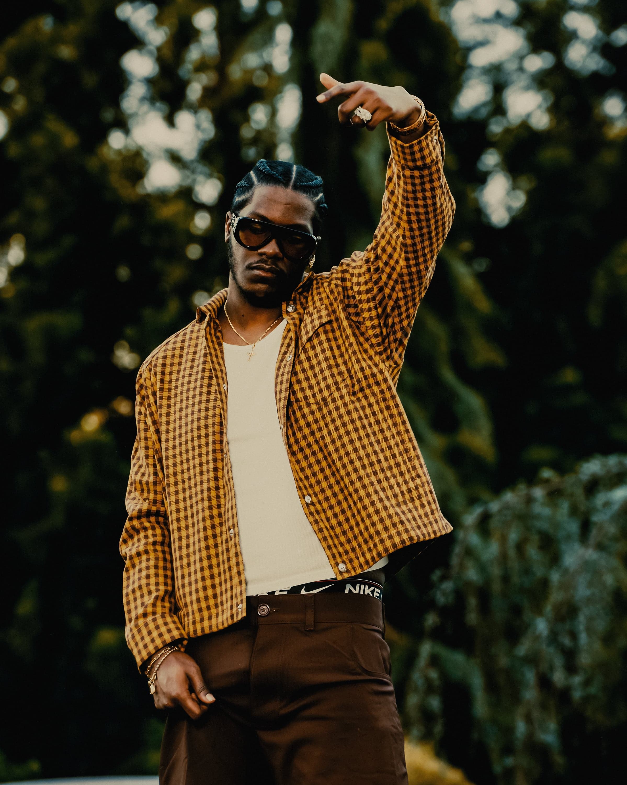 Lil Yachty and Shannon McCollum standing together outdoors at golden hour in matching plaid and suede